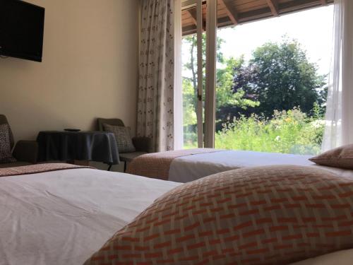 a bedroom with two beds and a large window at B&B La Romance du Lac in Robertville