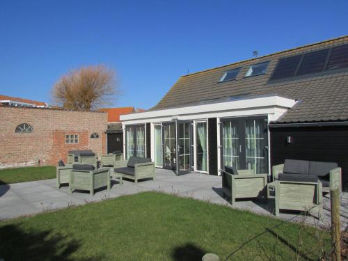 a patio with chaises and chairs in front of a house at De Dorsvloer in Domburg