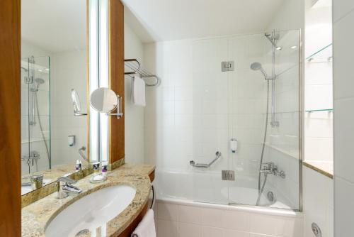 a bathroom with a sink and a shower at Mercure Hotel München Airport Freising in Freising