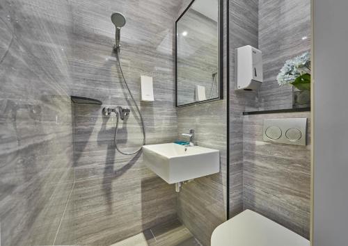 a bathroom with a white sink and a shower at Hotel 81 Orchid in Singapore