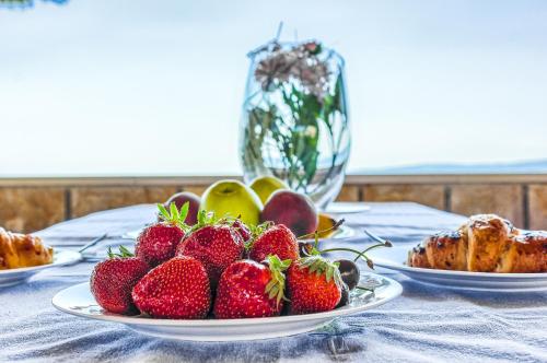 a table topped with plates of strawberries and other foods at Apartments & Bungalows Ivanović in Kaštela
