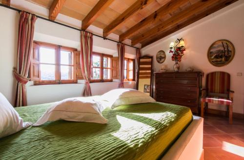 a bedroom with a green bed with a dresser and windows at Cocons in Sineu