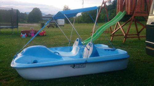 a blue boat sitting on the grass with a slide at Rybnik Dalibor in Vlcice