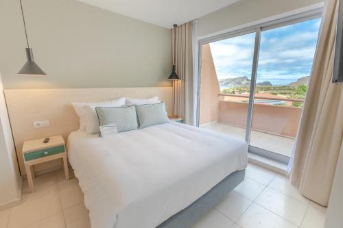 um quarto com uma cama grande e uma janela grande em Vila Baleira Porto Santo em Porto Santo