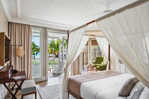 a bedroom with a canopy bed and a balcony at Heritage Le Telfair Golf & Wellness Resort in Bel Ombre