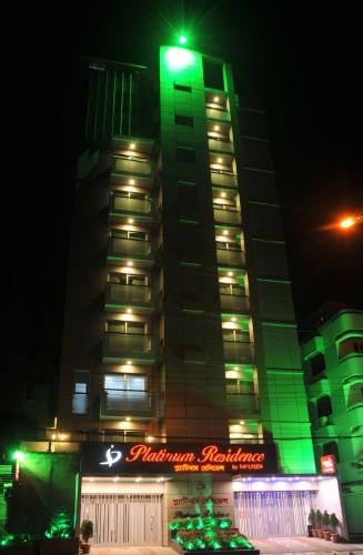 a tall building with green lights on it at night at Platinum Residence in Dhaka