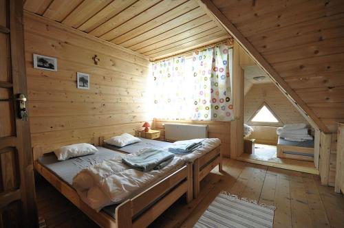 ein großes Bett in einem Holzzimmer mit Fenster in der Unterkunft Country Home in heart of Tatra mountains in Zakopane