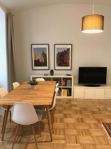 a dining room with a wooden table and a television at Apartments near Rathaus in Vienna