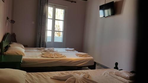 two beds in a room with a window at Markos Village Pension in Ios Chora