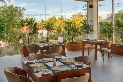a restaurant with tables and chairs and large windows at NorthGate Jaffna in Jaffna