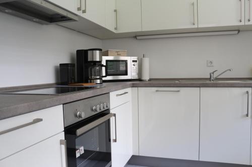 a kitchen with white cabinets and a microwave at Rosenweg in Beelen