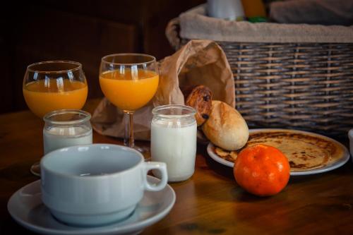 a table with a cup of coffee and two glasses of orange juice at Hôtel & Spa Chai De La Paleine in Le Puy-Notre-Dame