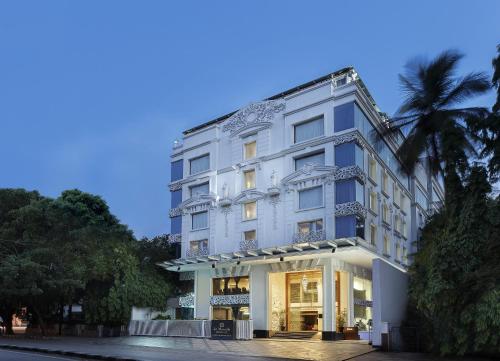 a white building with a palm tree in front of it at La Marvella, Bengaluru in Bengaluru