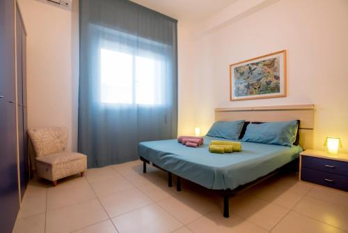 a bedroom with a bed and a chair and a window at DELPOSTO Marina di Ragusa (az) in Marina di Ragusa