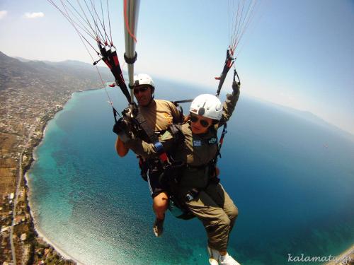 two people hanging from a parachute over the water at Kalamata Art Rooms in Kalamata