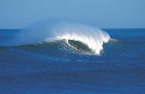 a person riding a wave on a surfboard in the ocean at Casa Boo de Piélagos - Playa de Liencres in Boó de Piélagos