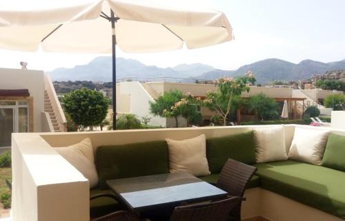 a green couch on a balcony with a table and an umbrella at Lagada Resort in Makry Gialos