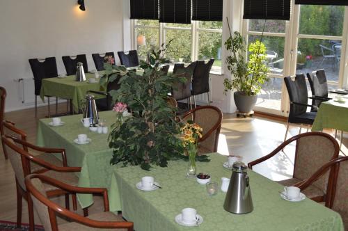 un restaurante con mesas verdes y sillas con flores. en Hotel E4, en Rødby