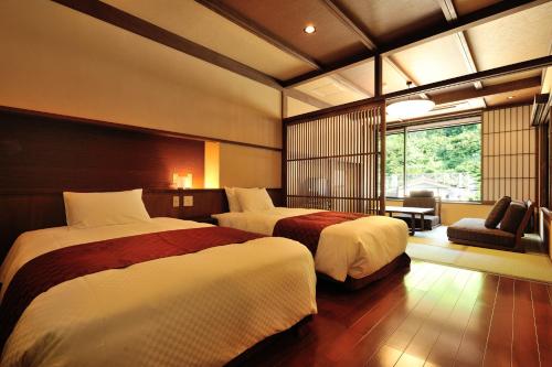 a hotel room with two beds and a window at Hinanoyado Chitose in Tokamachi