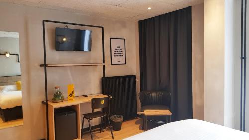 a bedroom with a bed and a desk with a television at Upstairs Hotel in Ostend