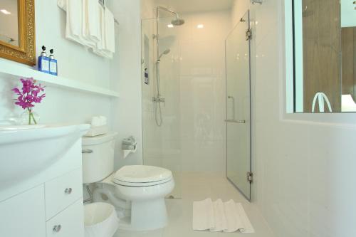 a white bathroom with a toilet and a shower at Villa Amphawa in Amphawa