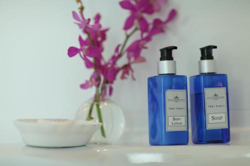 three bottles of soap and a vase with purple flowers at Villa Amphawa in Amphawa