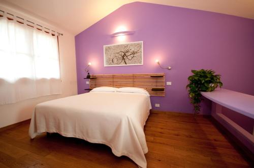 a bedroom with purple walls and a white bed at Hotel La Posta di Torrenova in Orbetello