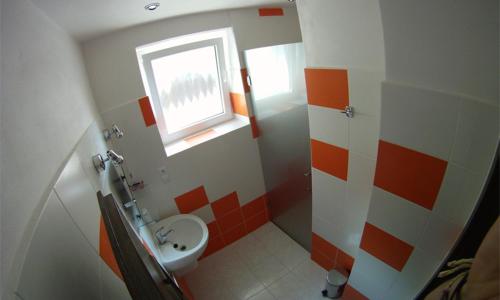 an orange and white bathroom with a sink and a window at Penzion pod vejmutovym lesom in Kremnica