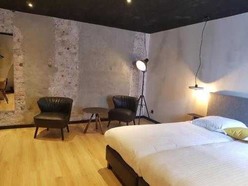 a bedroom with a bed and two chairs and a table at Upstairs Hotel in Ostend