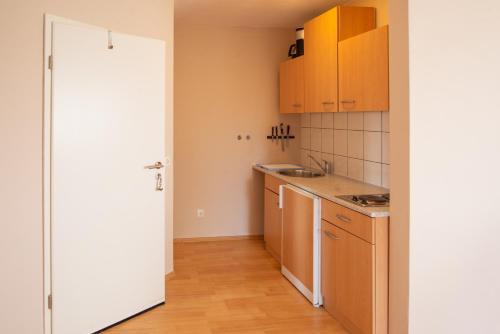 a small kitchen with wooden floors and cabinets at Appartementhaus Badria in Bad Füssing