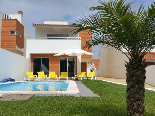 a villa with a swimming pool and a palm tree at Modern Villa in S o Martinho do Porto with Swimming Pool in São Martinho do Porto