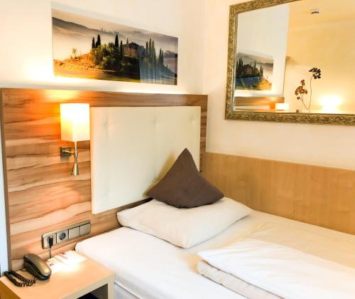 a bedroom with a bed and a mirror and a phone at City Hotel Ost am Kö in Augsburg