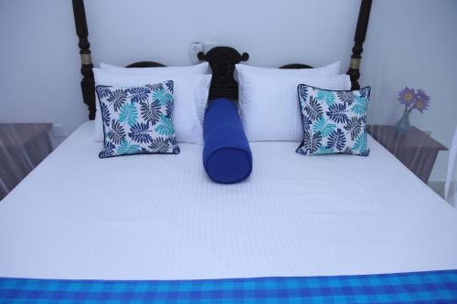 a white bed with pillows and a tie on it at Villa Gaetano Unawatuna in Unawatuna