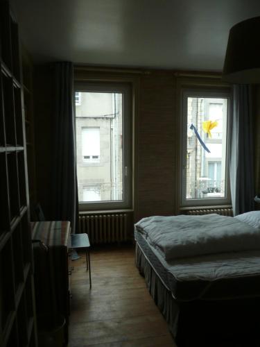 1 dormitorio con 2 ventanas, 1 cama y 1 mesa en 81 Rue des Juifs, en Granville