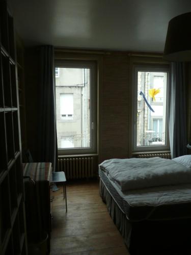 a bedroom with two windows and a bed and a table at 81 Rue des Juifs in Granville