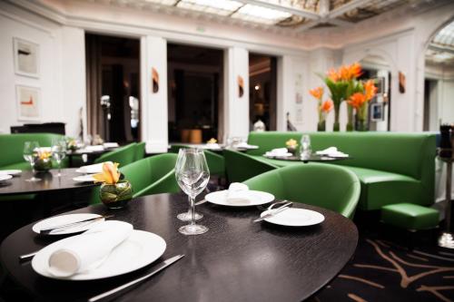 a dining room with tables and green chairs at Hôtel Vernet Champs Elysées Paris in Paris