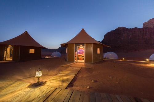 a couple of huts in the desert at night at Memories Aicha Luxury Camp in Wadi Rum