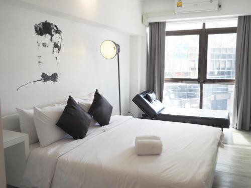 a bedroom with a white bed with a chair and a window at 3Howw Hostel @ Sukhumvit 21 in Bangkok
