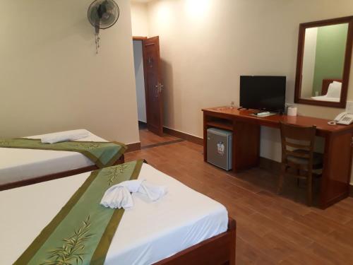 a room with two beds and a desk with a computer at Tabii hotel in Da Nang