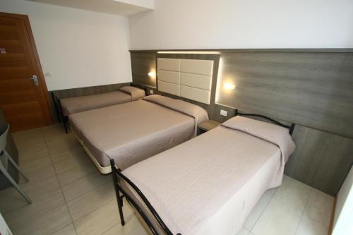 a room with two beds and a door and a room with two at Hotel Boom in Rimini