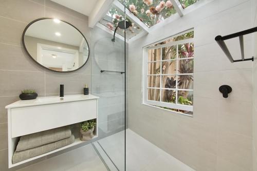 La salle de bains blanche est pourvue d'un lavabo et d'un miroir. dans l'établissement Paddington Garden Cottage with fast Wifi, à Sydney