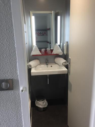 ein Bad mit einem Waschbecken und einem Spiegel in der Unterkunft Enzo Hotels Trappes by Kyriad Direct in Trappes