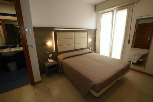 a bedroom with a bed and a bathroom with a sink at Hotel Boom in Rimini
