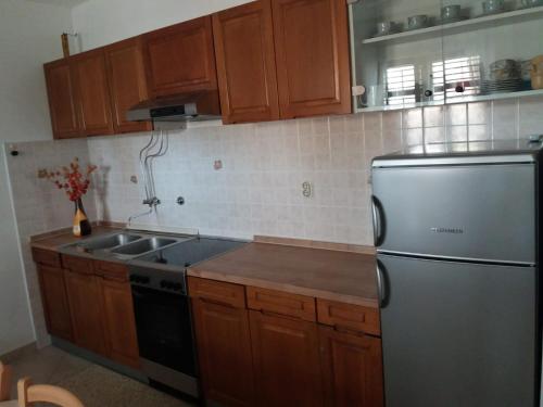 a kitchen with wooden cabinets and a stainless steel refrigerator at Apartments Stipanovic in Biograd na Moru