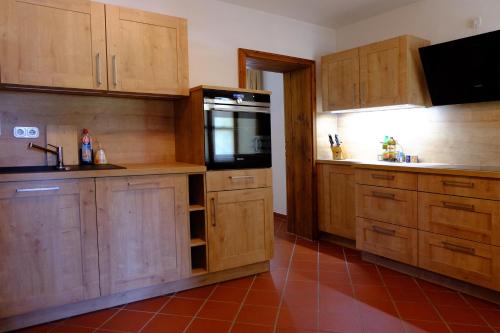 a kitchen with wooden cabinets and a black refrigerator at Hotel Schlossresidenz Heitzenhofen in Duggendorf