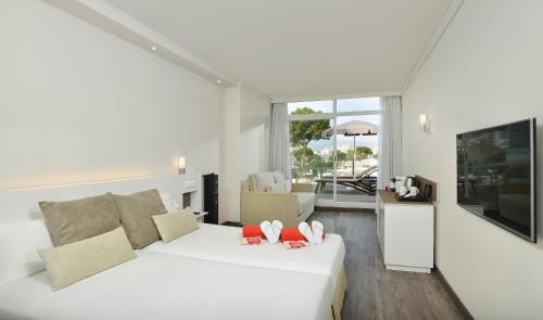 a white bedroom with a bed and a living room at Sol Barbados in Magaluf