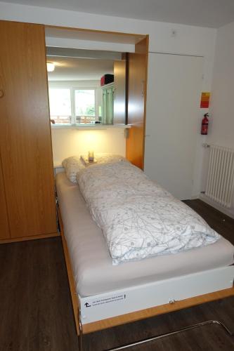 a bed in a small room with a light on it at Studio Willimann Haus Dala im 4 Stock in Leukerbad