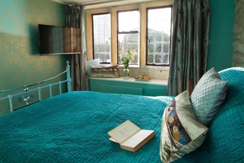 a bedroom with a blue bed with a book on it at St.Michaels Bistro in Painswick