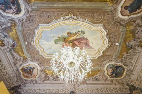 a chandelier hanging from a ceiling with paintings at Hotel Ai Cavalieri di Venezia in Venice