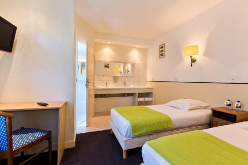 a hotel room with two beds and a desk at Logis Hôtel de la Paix in Saint-Nectaire